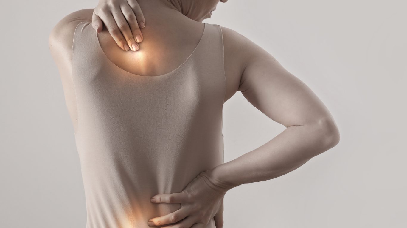 A person holding their neck and lower back in pain